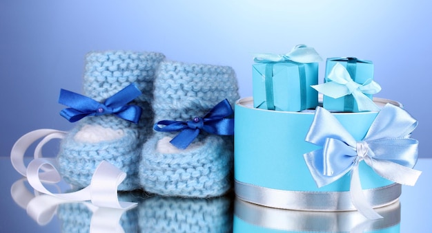 Beautiful gifts and baby's bootees on blue background