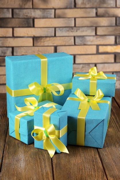 Beautiful gifts on table on brick wall background