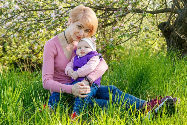 Beautiful girl in the arms of a child girl in a blooming park closeup