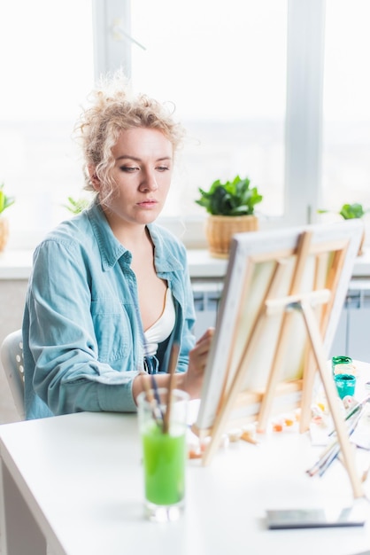 Beautiful girl artist paints on canvas at home