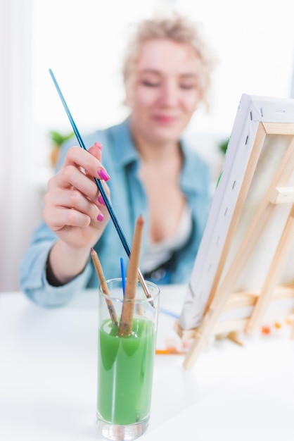 Beautiful girl artist paints on canvas at home