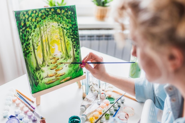 Beautiful girl artist paints on canvas at home