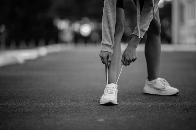 beautiful girl athlete sitting tying shoelaces on white sneakers black and white photo