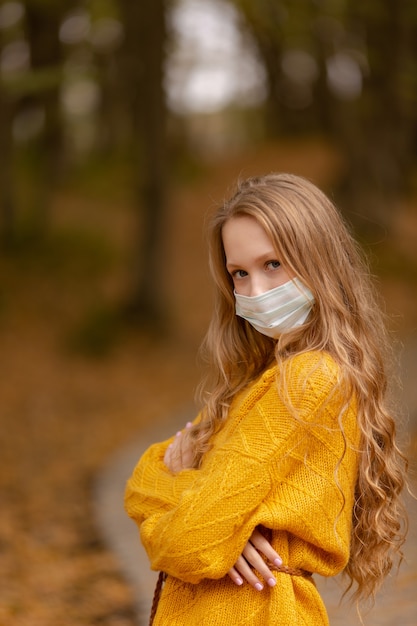 beautiful girl in autumn in a medical mask