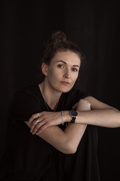 Beautiful girl in black clothes. Portrait of an attractive middle-aged woman in a dark room.