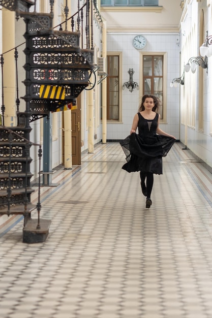 Beautiful girl in black dress running in hall checkered floor