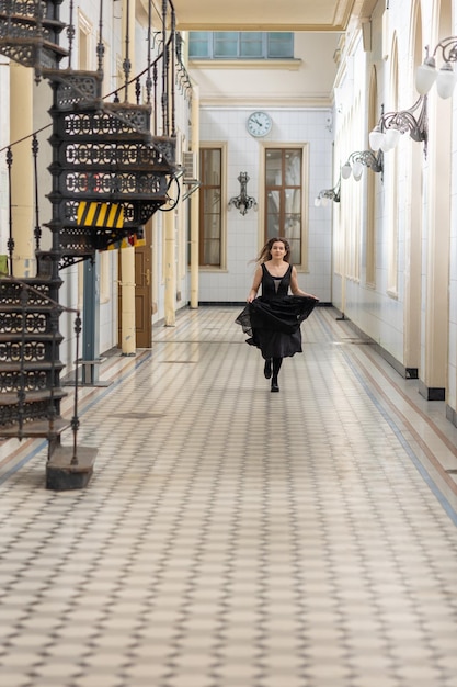 Beautiful girl in black dress running in hall checkered floor