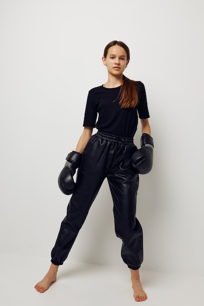 Beautiful girl in black sports uniform boxing gloves posing isolated background