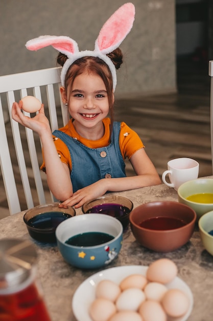 Beautiful girl in bunny ears paint easter eggs