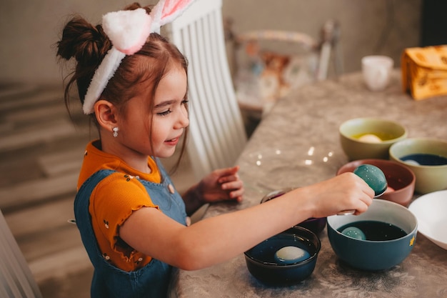 Beautiful girl in bunny ears paint easter eggs