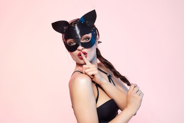 Beautiful girl in a cat mask playfully posing in front of the camera