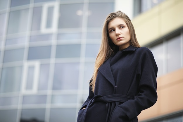 Beautiful girl in a coat in business downtown of the cloudy