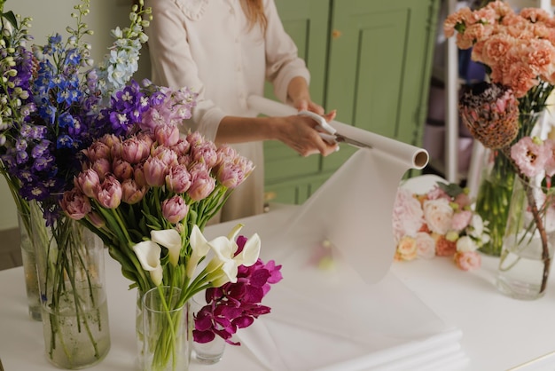 Beautiful girl collects a bouquet of flowers in a flower shop