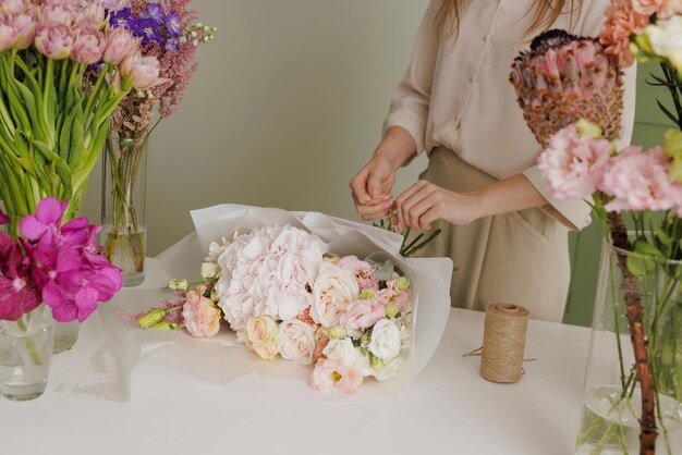 Beautiful girl collects a bouquet of flowers in a flower shop