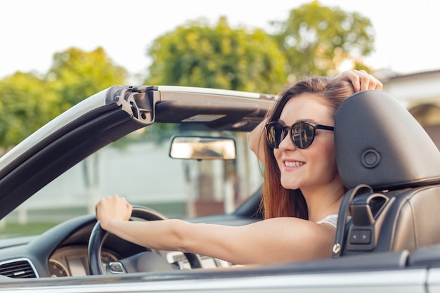 Beautiful girl in the  convertible cabrio car on a sunny day in a city