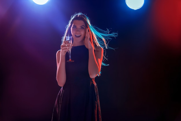 The beautiful girl dancing at the party drinking champagne