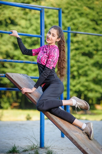 Beautiful girl doing fitness exercises in park. Summer time