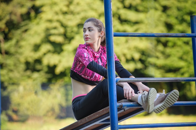 Beautiful girl doing fitness exercises in park. Summer time