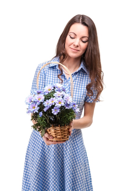 Beautiful girl in a dress in a blue cage with flowers chrysanthemums in hands on a white background