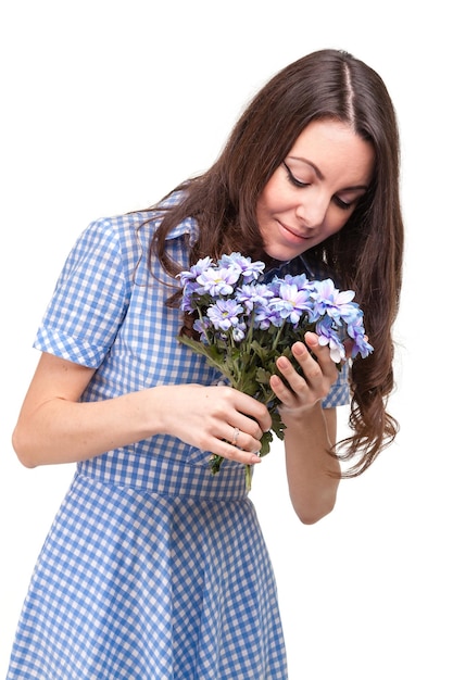 Beautiful girl in a dress in a blue cage with flowers chrysanthemums in hands on a white background