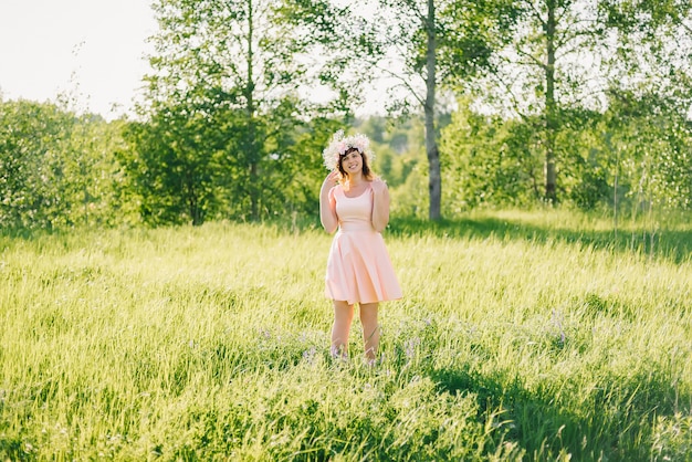 Beautiful girl in a dress of Caucasian appearance with a wreath on her head on a meadow