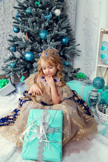 Beautiful girl in dress near Christmas tree