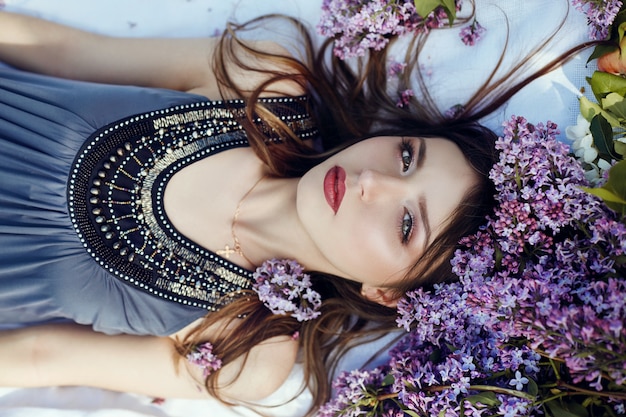 Beautiful girl dress posing lying lilac branches