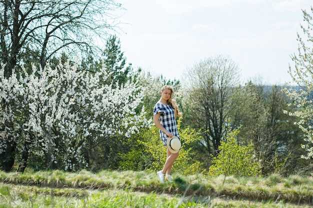 Beautiful girl in a dress walking in the spring forest where the trees bloom