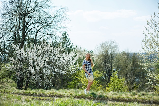 Beautiful girl in a dress walking in the spring forest where the trees bloom