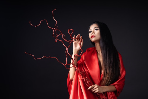 Beautiful girl dressed as a geisha in a red kimono with a fan