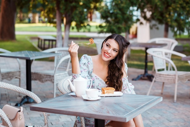 Beautiful girl enjoying her meal delicious honey cake spending time in outdoor cafe in summer