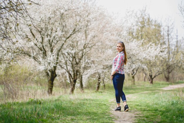 Photo beautiful girl in flowering trees in early spring. bright sun and nature