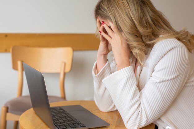 Beautiful girl freelancer feeling tired and stressed while using a laptop and working remotely.