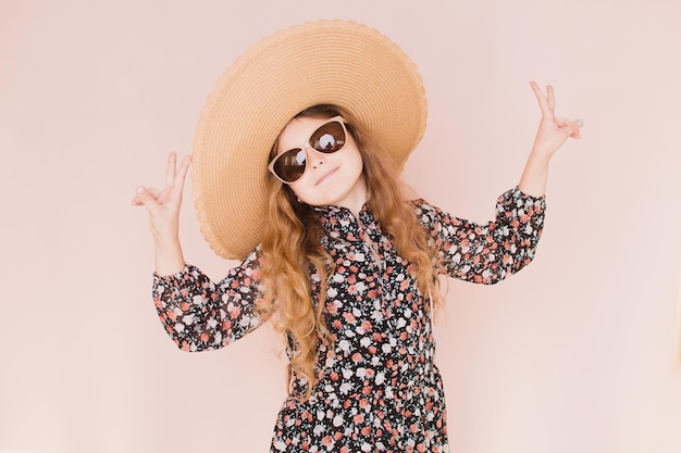 Beautiful girl in glasses and a hat on a pink background