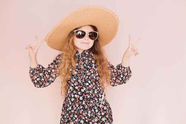 Beautiful girl in glasses and a hat on a pink background