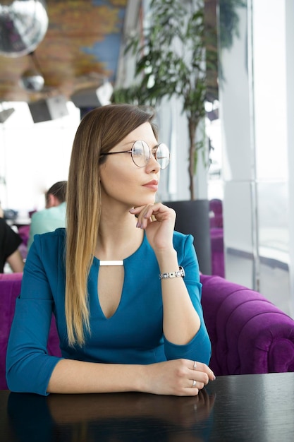 Beautiful girl in glasses sitting in a cafe