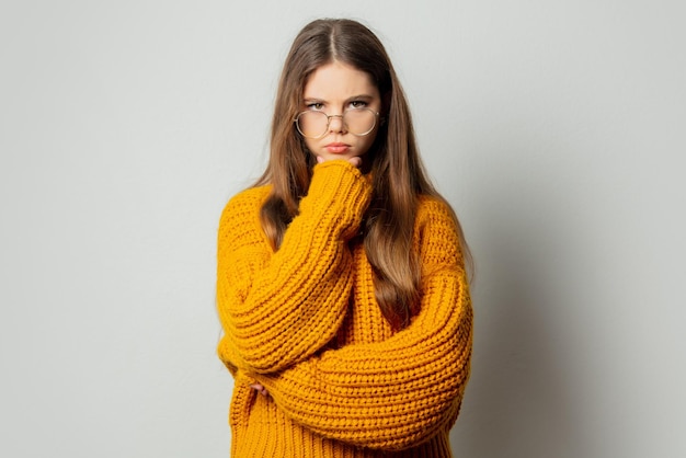 Beautiful girl in glasses and yellow sweater on white background