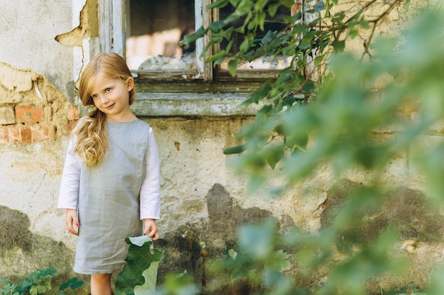 beautiful girl in a gray dress with a leaf in her hands standing on the grass 