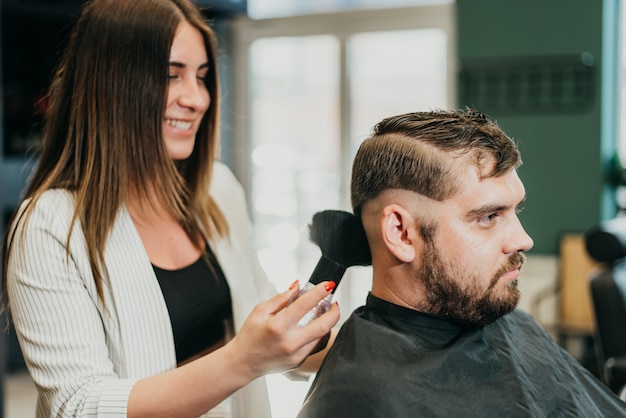 Beautiful girl hairdresser cuts a bearded man in the salon