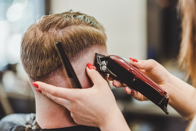 Beautiful girl hairdresser cuts a bearded man in the salon