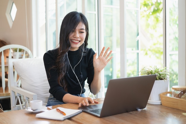 Beautiful girl in headphones using laptop at cafe, having video conference, free space