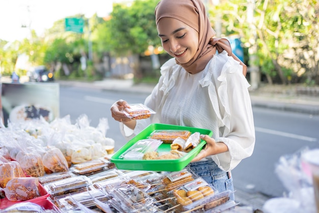 A beautiful girl in a headscarf holding a plastic tray to place a selection of side dishes purchased