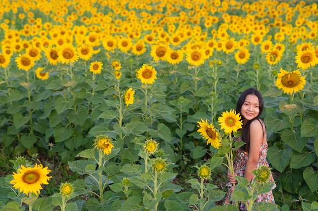 Beautiful girl hold sunflower standing at flower filed background