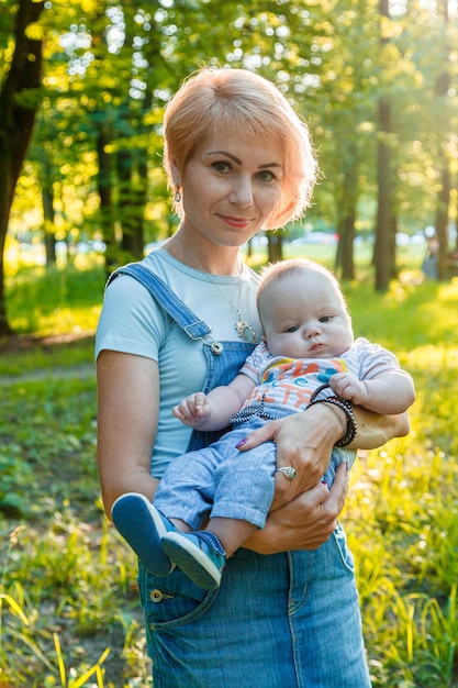 Beautiful girl holding a child in her arms in a summer park