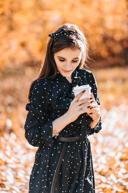 Beautiful girl holding a glass of coffee on a Sunny autumn day