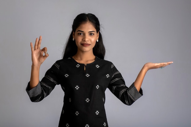 Beautiful girl holding and presenting something in the hand with a happy smiling face.