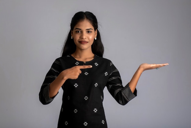 Beautiful girl holding and presenting something in the hand with a happy smiling face.