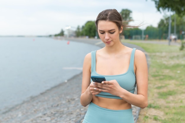 A beautiful girl holds a phone in her hands and looks at the phone Stylish girl with a phone