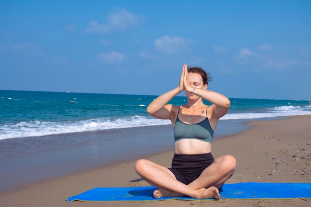 A beautiful girl is doing yoga on the beach near the sea