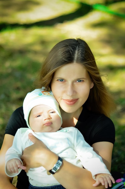 Beautiful girl is holding a baby girl walking with a baby in the park outdoors